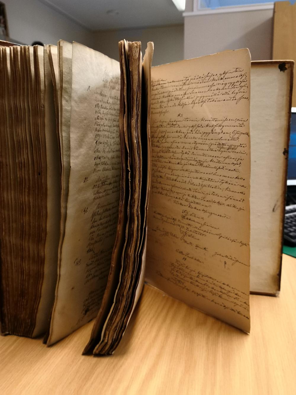 Vanha kirja pystyssä pöydällä. Kirjassa käsikirjoitettuja kirkkoneuvoston pöytäkirjoja vuosilta 1845-1873.